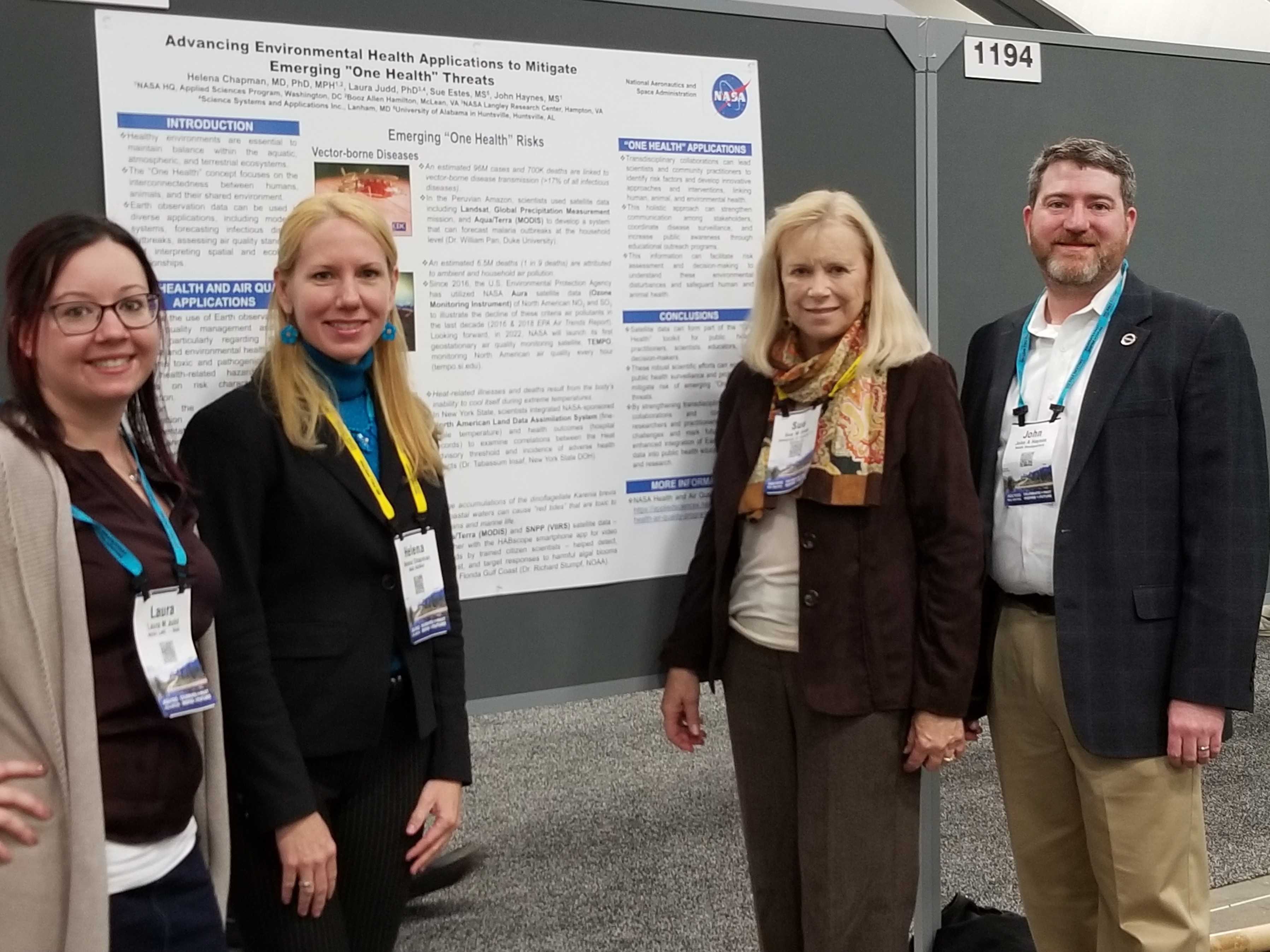 four people standing in front of a poster