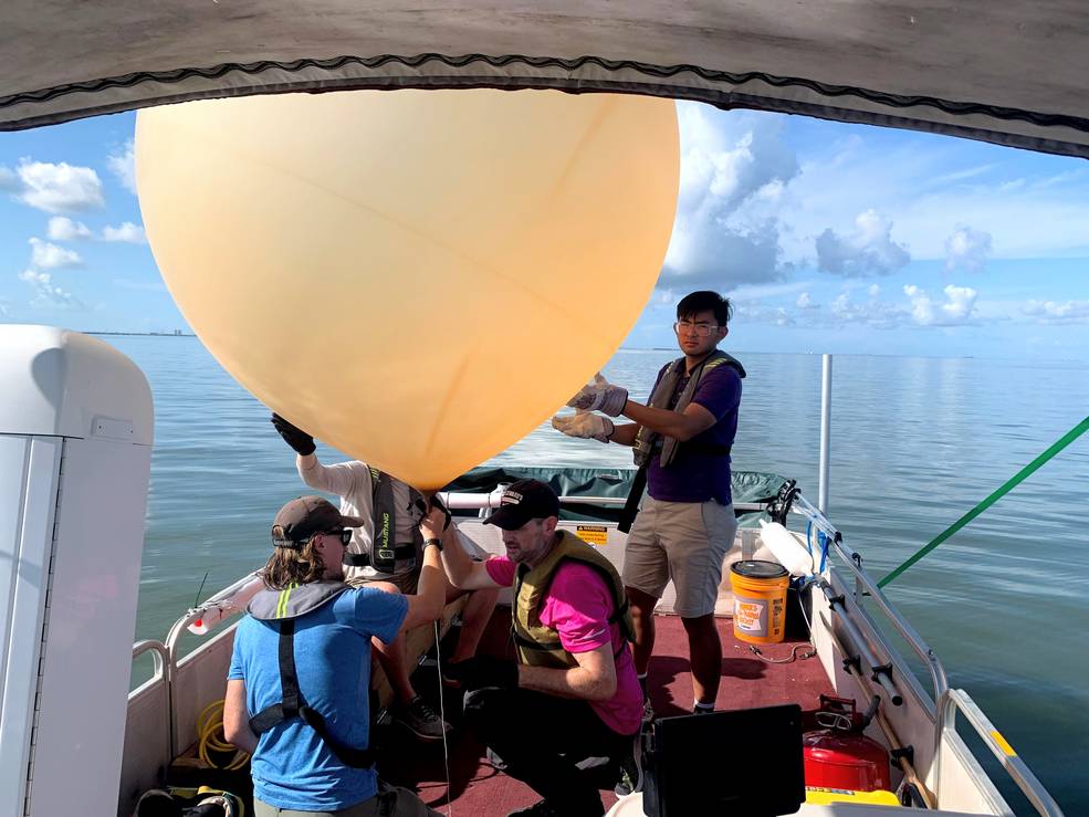 four people on boat with large research balloon