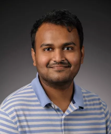 Man in blue striped shirt smiles in portrait 