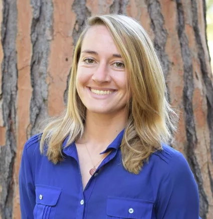 Woman with blonde hair in a blue shirt smiles for picture