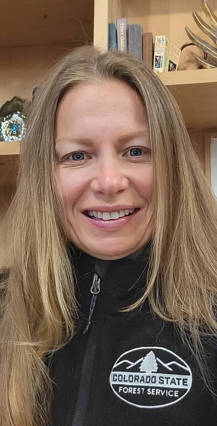 Woman with long hair in a Colorado State Forest Service jacket smiles