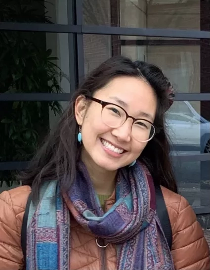 Woman in puffy coat and scarf smiles for picture 