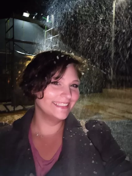 Woman with short hair smiles in the rain at night