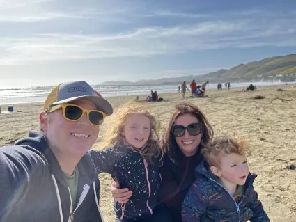 Father, mother, and two children smile for picture on the beach 