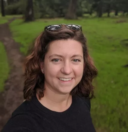 Woman with sunglasses in wavy hair smiles for portrait 