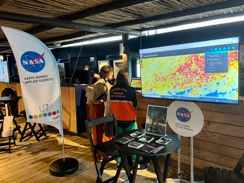 Gabriella Lewis, NASA Disasters program science writer, chats with a visitor at the NASA booth. Credits: NASA