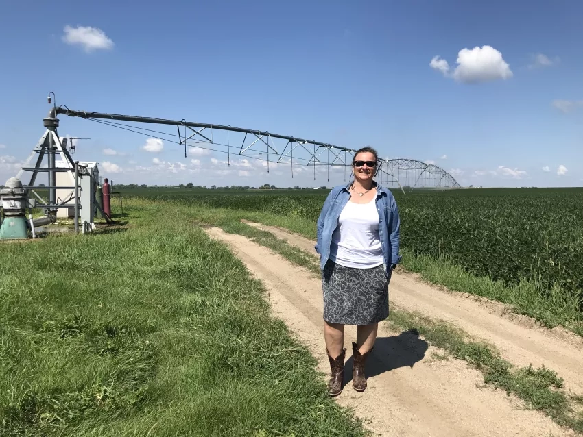 white woman wearing sunglasses standing in front of a large silver silo