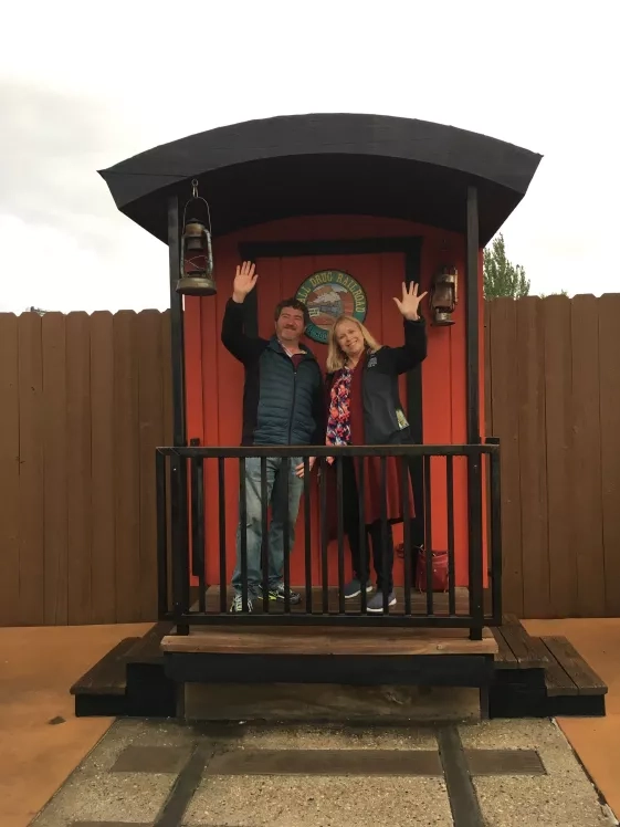 two people waving on train caboose