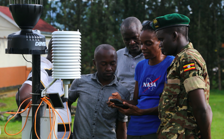 Photo of scientist showing instrument to government staff