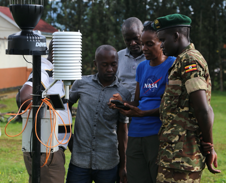 Photo of scientist showing instrument to government staff