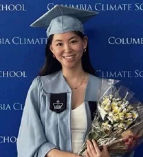 Molly smiles dressed in her graduation attire from Columbia University.