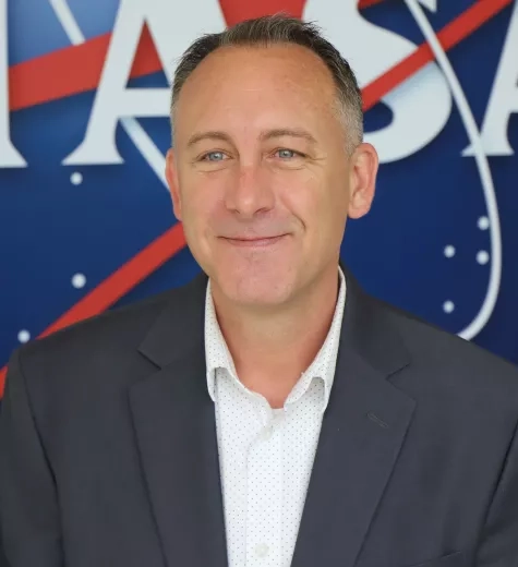 Image of Brock in front of the original NASA logo