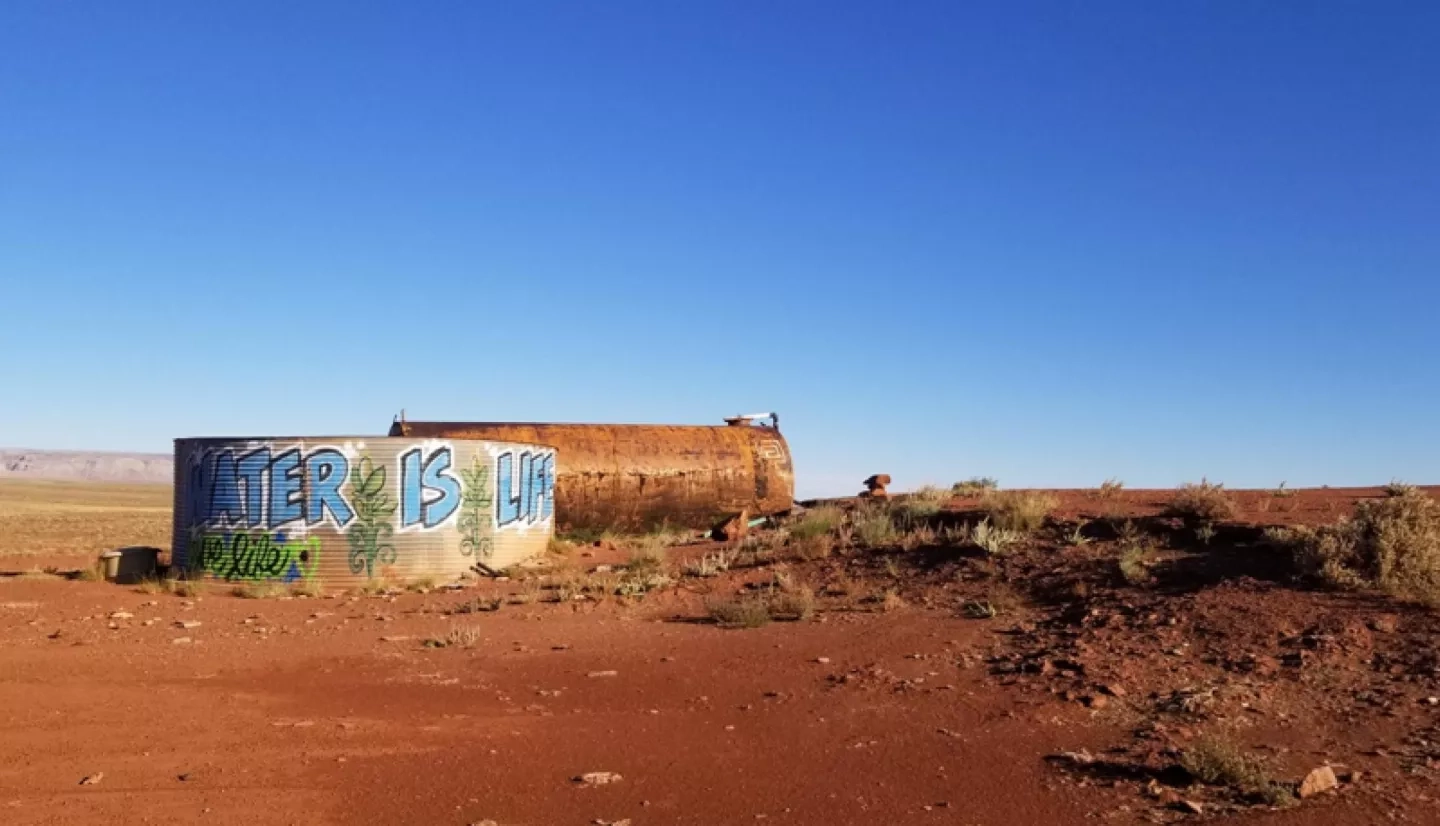 water tank in desert with "Water is Life" graffiti