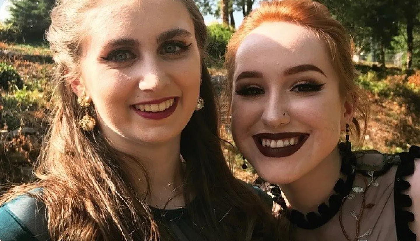 Two women stand together, smiling.