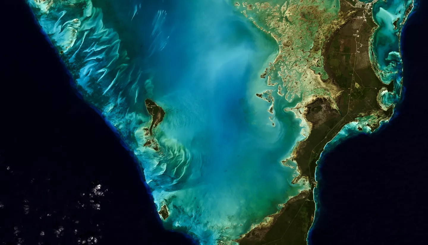 satellite image of Bahamas with teal shallow waters surrounded by dark blue ocean