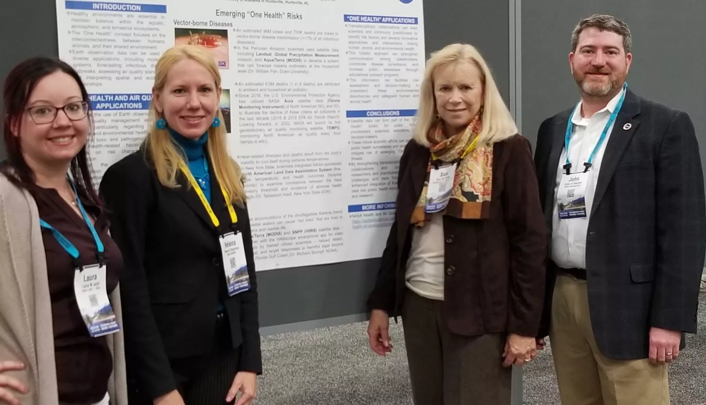 four people standing in front of a poster