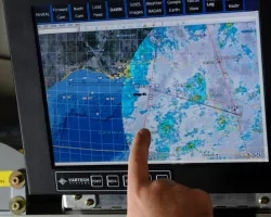 A researcher points out the trajectory of a weather pattern on a computer monitor during a flight aboard the NASA DC-8 aircraft