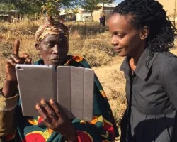 Photo of scientist showing iPad data to a Ugandan expert