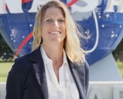 blonde woman smiling in front of NASA logo