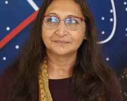 Amita pictured standing in front of the original NASA logo