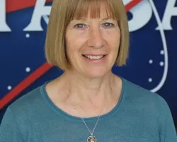 Photo of Annelise Carleton-Hug in front of the original NASA logo