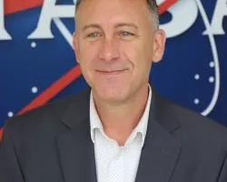 Image of Brock in front of the original NASA logo