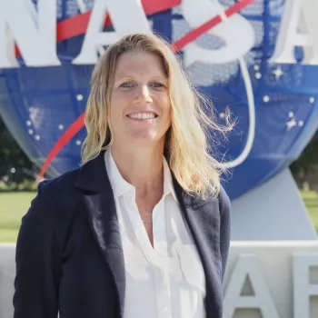 blonde woman smiling in front of NASA logo