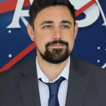 Jonathan pictured standing in front of the original NASA logo