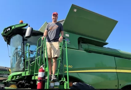 Man standing on stairs near cab of massive tractor