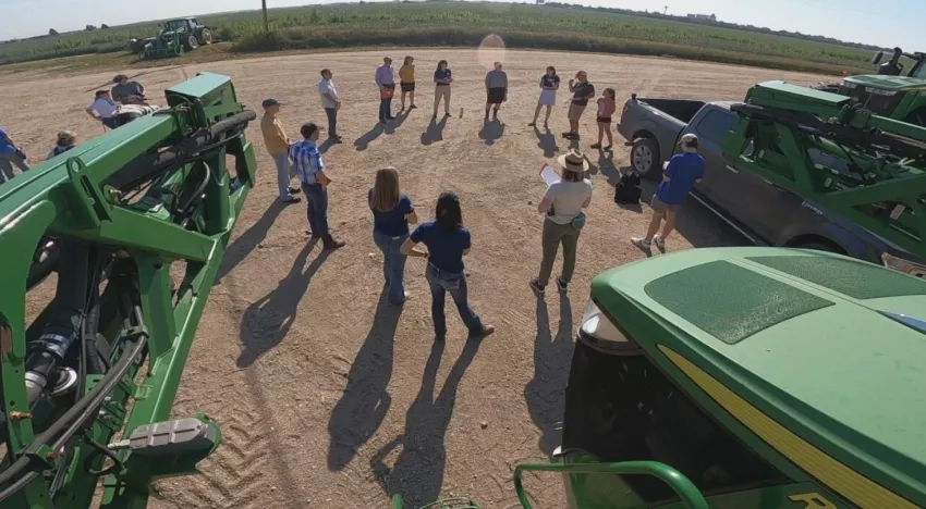 view from a high vantage point of a group of people standing near tractors in a field