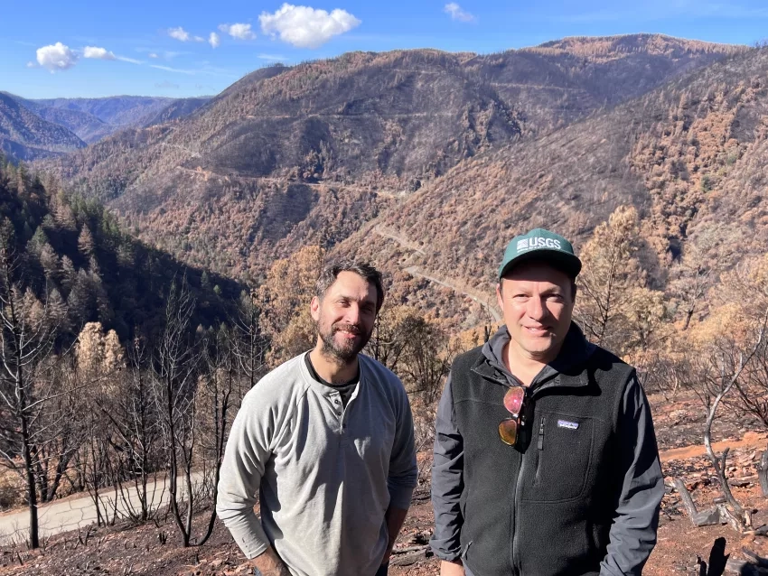 Photo of two men standing in front of a landscape